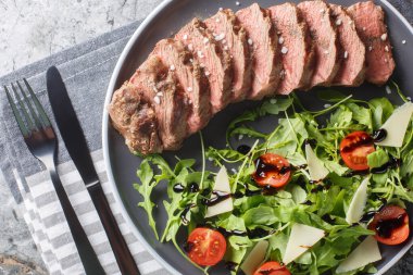 Biftekli tagliata roka, parmesan peyniri, vişneli domates ve bir tabakta yakın plan balzamik. Yukarıdan yatay üst görünüm