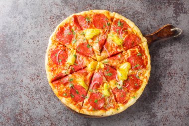 Salamlı dilimlenmiş pizza, Pepperoncini, mozzarella, şifalı otlar ve kırmızı soğanlar masanın üzerinde yakın plan. Yukarıdan yatay üst görünüm