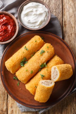 Polonya Krokiety Kroketleri, ahşap masadaki tabakta yakın plan tavada kızartılmış, doldurulmuş ve kızartılmış gözlemelerdir. Yukarıdan dikey üst görünüm