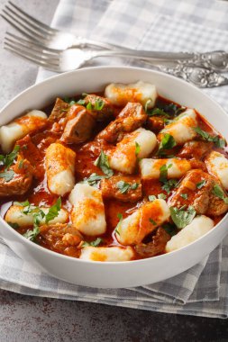 Kaynamış patates köftesi Kopytka et sosunu yakın planda, masanın üstünde. Dikey