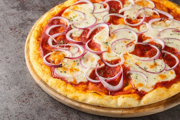 Domates soslu İtalyan pizzası, erimiş peynir ve masanın üzerindeki tahta tahtada yakın plan kırmızı soğan. Yatay