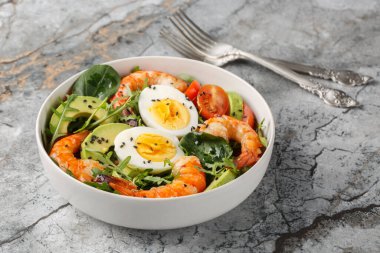 Masada karides, avokado, roka, ıspanak, domates, susam tohumu ve haşlanmış yumurta ile servis edilen lezzetli salata. Yatay