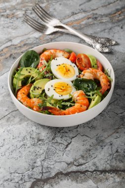 Akdeniz karides salatası, avokado, roka, ıspanak, domates ve haşlanmış yumurtaları masanın üstünde yakın plan. Dikey