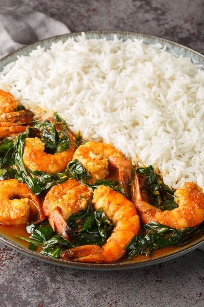 Delicious Indian prawn and spinach curry served with rice closeup on the plate on the table. Vertica