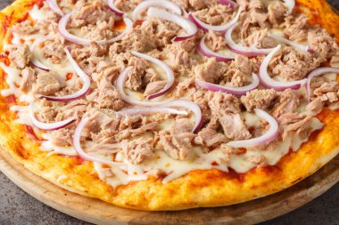 Domates soslu geleneksel pizza ton balığı, konserve ton balığı, mozzarella peyniri ve masanın üzerindeki ahşap tahtaya yakın plan kırmızı soğan. Yatay