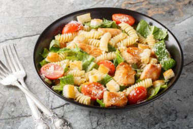 Makarna soslu tavuklu Sezar Salatası, romaine marulu, parmesan peyniri, domates ve kızarmış ekmekler masanın üstünde. Yatay
