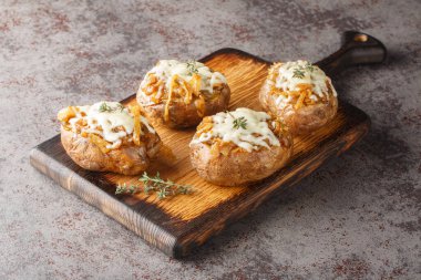 Fransız soğanı ve Gruyere peyniri ile doldurulmuş fırında pişirilmiş patates tabağı masanın üstünde. Yatay