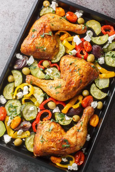 Greek Sheet Pan Chicken With Vegetables and Feta closeup on the table. Vertical top view from abov