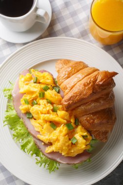 Omlet, jambon, yeşil soğan ve portakal suyu ile servis edilen marul ve mermer bir masada yakın plan kahve ile taze kruvasan. Yukarıdan dikey üst görünüm