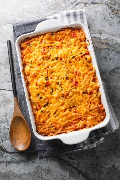 stock image King Ranch Chicken Casserole with pulled chicken, corn tortillas, shredded cheese, peppers, and spicy green chiles close-up in a baking dish on a marble table. Vertical top view from abov