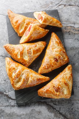 Sosisli, peynirli ve biberli sosisli börekler masada mermer bir tahtanın üzerinde. Yukarıdan dikey üst görünüm