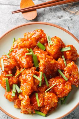 Gobi mançurya usulü yağda kızartılmış karnabahar ekşi sosla sotelenmiş masanın üzerindeki tabağa yakın çekim. Yukarıdan dikey üst görünüm