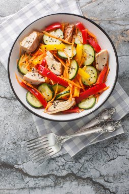Fırında tavuk, salatalık, biber, havuç ve susam tohumlu taze salata, masanın üstünde. Yukarıdan dikey üst görünüm