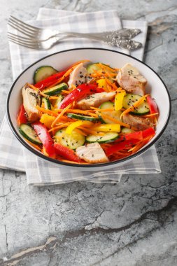 Fırında tavuk, salatalık, biber, havuç ve susam tohumlu taze salata, masanın üstünde. Dikey