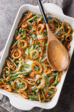 Yeşil fasulye güveci ve kızarmış soğan, masadaki fırın tabağının üzerine yakın plan kremalı mantar sosunun içine atılıyor. Yukarıdan dikey üst görünüm