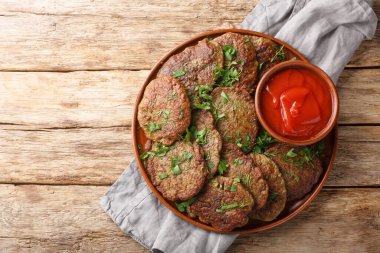 Domates sosuyla servis edilen leziz diyet ciğer köfteleri ve masada yakın plan otlar. Yukarıdan yatay üst görünüm