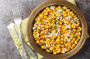 Meksika sokak mısırı Esquites, soslu, biberli, soğanlı ve peynirli tabakta yakın plan. Yukarıdan yatay üst görünüm