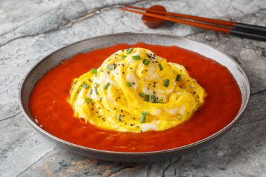 Kızarmış pilavın üstünde tornado omleti, susam tohumları, yeşil soğan ve masada yakın plan acı biber sosu. Yatay