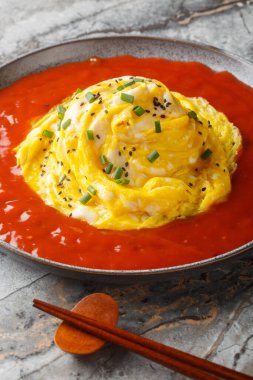 Kızarmış pilav üzerine Kore kasırgası omleti ve masanın üzerindeki sıcak sos tabağına yakın çekim. Dikey