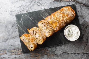 Tavuklu, mantarlı ve peynirli çörek. Masanın üstünde sosla servis ediliyor. Yukarıdan yatay üst görünüm