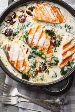 Masadaki tavada ıspanaklı ve güneşte kurutulmuş domatesli lezzetli Toskana kremalı somon. Yukarıdan dikey üst görünüm