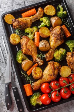 Sağlıklı yemek pişirilmiş tavuk budu brokoli, patates, domates ve havuçlar masanın üzerinde yakın plan. Yukarıdan dikey üst görünüm