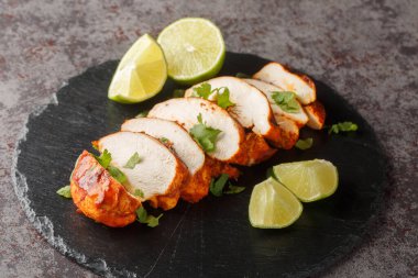 Limon ve kişniş ile servis edilen dilimlenmiş ızgara chipotle tavuk göğsü masaya yakın plan. Yatay