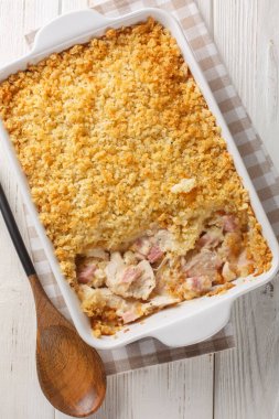 Tavuk göğsü, peynir ve jambonlu Cordon Bleu güveci beyaz ahşap masadaki fırın kabında krema kaplamasında eritildi. Yukarıdan dikey üst görünüm