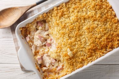 Tavuklu Cordon Bleu güveci, sıcak ve rahatlatıcı bir hafta sonu yemeği. Beyaz ahşap masadaki fırın kabının içinde. Yukarıdan yatay üst görünüm