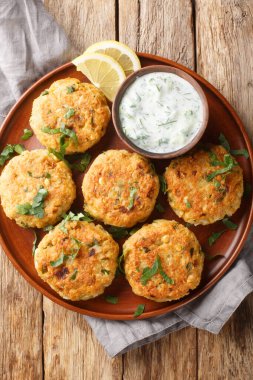 Tzatziki soslu nohut böreği ahşap bir masada yakın plan bir tabakta. Yukarıdan dikey üst görünüm