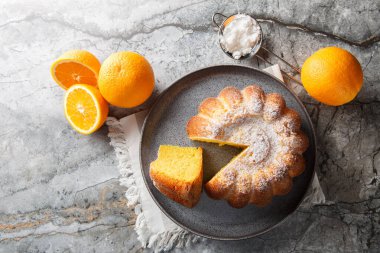 Lezzetli portakallı kek ve portakal suyu. Masanın üzerine pudra şekeri serpiştirilmiş. Yukarıdan yatay üst görünüm
