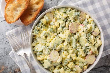 Turplu yumurta salatası, yeşil soğan ve mayonez kaplı salatalık. Masadaki kaseye yakın plan. Yukarıdan yatay üst görünüm