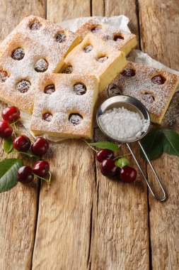 Bublanina turtası taze, sulu yaz kirazı yumuşak bir sünger pastayla kaplanmış ahşap masadaki parşömene yakın. Dikey