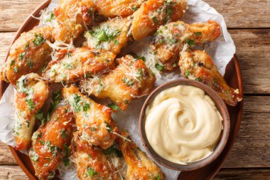 Parsley Garlic Parmesan chicken wings served with dipping sauce close-up in a plate on the table. Horizontal top view from abov