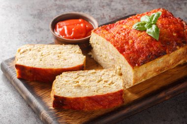 Dilimlenmiş tavuklu rulo köfte. Masadaki tahtanın üzerinde ketçapla servis ediliyor. Yatay