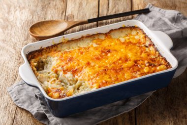 Ev yapımı peynirli haşlanmış güveç, ahşap masadaki fırın tabağında patates ve krema yakın plan. Yatay