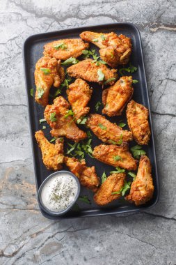 Kızarmış körili tavuk kanatları masanın üzerindeki bir tabakta yakın plan. Yukarıdan dikey üst görünüm