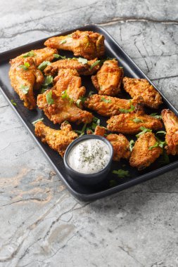 Kızarmış körili tavuk kanatları masanın üzerindeki bir tabakta yakın plan. Dikey