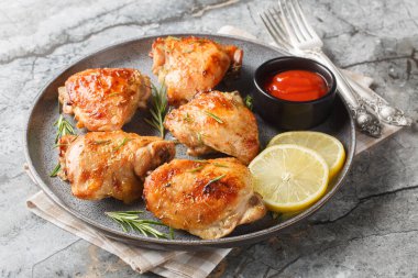 Salamuraya yatırılmış ve fırında pişirilmiş tavuk butları limon ve biberiyeyle servis edilmiş ketçap yakın plan bir tabakta masada. Yatay