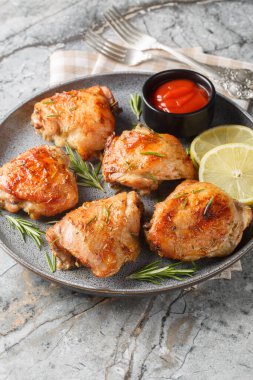 Biberiyeyle pişirilmiş tavuk butları, limon suyu ve lezzetli yakın plan bir tabakta masanın üstünde. Dikey