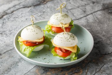 Peynirli, pastırmalı, domatesli ve marullu haşlanmış yumurta dilimleri masanın üstünde. Yatay