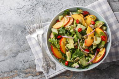 Şeftali, avokado, salatalık, kırmızı soğan, kırmızı biber, roka, ıspanak ve kabak tohumlu taze yaz salatası. Yukarıdan yatay üst görünüm