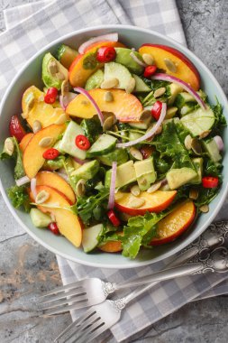 Şeftalili avokado salatası, soğan, biber, roka, ıspanak ve kabak çekirdekleri masanın üstünde. Yukarıdan dikey üst görünüm
