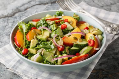 Nektarinli baharatlı salata, avokado, salatalık, kırmızı soğan, kırmızı biber, roka, ıspanak ve kabak çekirdekleri masanın üzerinde. Yatay