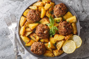 Yunan usulü bifteki köfteler ve masaya yakın duran limonlu patatesler. Yukarıdan yatay üst görünüm