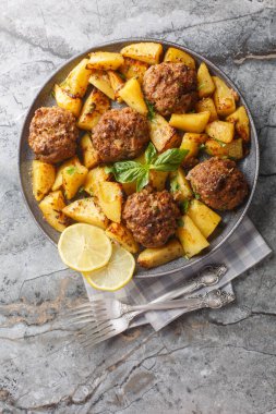 Bifteki Yunan usulü fırınlanmış biftek ve patates dilimleri limon zeytinyağı sosu. Masanın üzerindeki tabağa yakın. Yukarıdan dikey üst görünüm