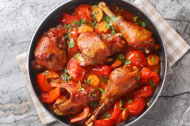 Yavaşça pişirilmiş horoz, biberli, soğanlı ve havuçlu domates soslu, masanın üstünde yakın plan bir tavada. Yukarıdan yatay üst görünüm