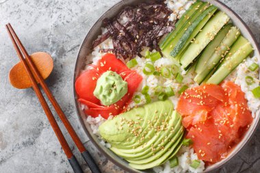 Japon suşi kasesi somon, pirinç, sebze, yosun, zencefil ve wasabi ile masaya yakın çekim. Yukarıdan yatay üst görünüm