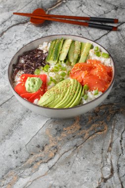 Somon, avokado, salatalık, beyaz pirinç, susam, zencefil ve wasabi kapaklı suşi kasesi. Dikey