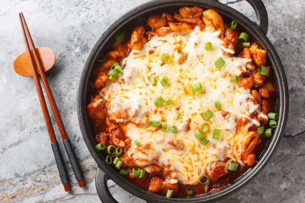 stock image Buldak is a popular Korean spicy chicken dish served as a street food or light meal closeup on the pan on the table. Horizontal top view from abov